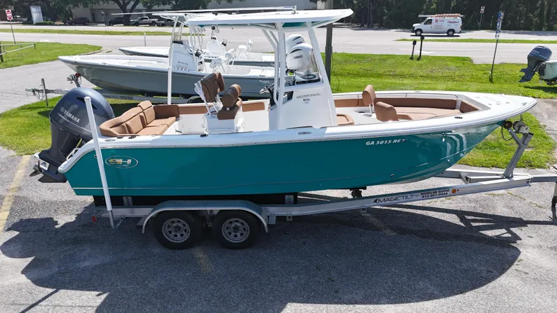 Slide: The Image of 2022 Sea Hunt 229 ULTRA boat on trailer, teal hull, parked outdoors. - 2