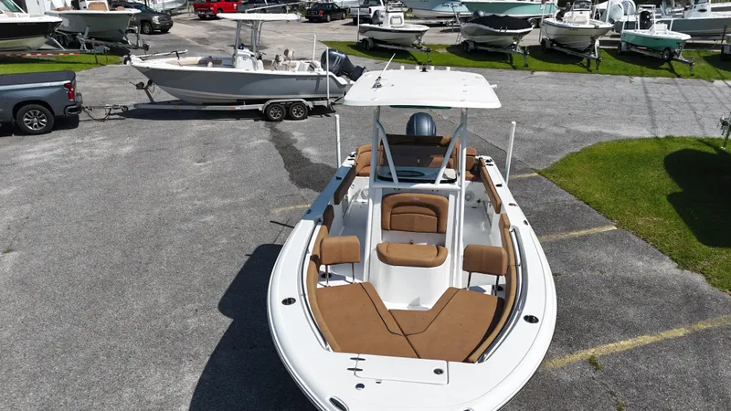 Slide: The Image of 2022 Sea Hunt 229 ULTRA boat with tan seating, parked on a trailer in a marina. - 4