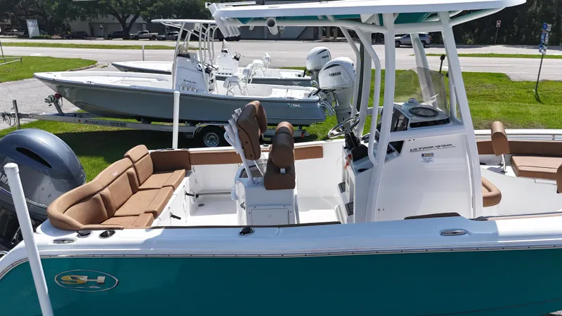 Slide: The Image of 2022 Sea Hunt 229 ULTRA boat with teal hull and brown seating, docked outdoors. - 9