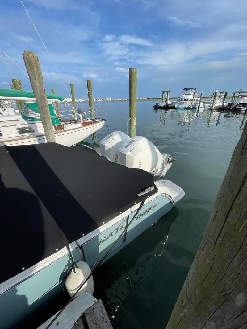 Slide: The Image of 2021 Sailfish 276 DC boat docked with twin engines, covered, in a marina. - 12