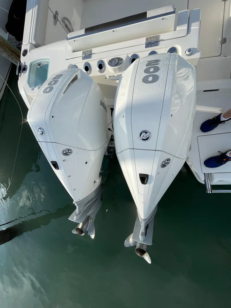 Slide: The Image of 2021 Sailfish 276 DC boat with dual outboard engines, docked on calm water. - 17
