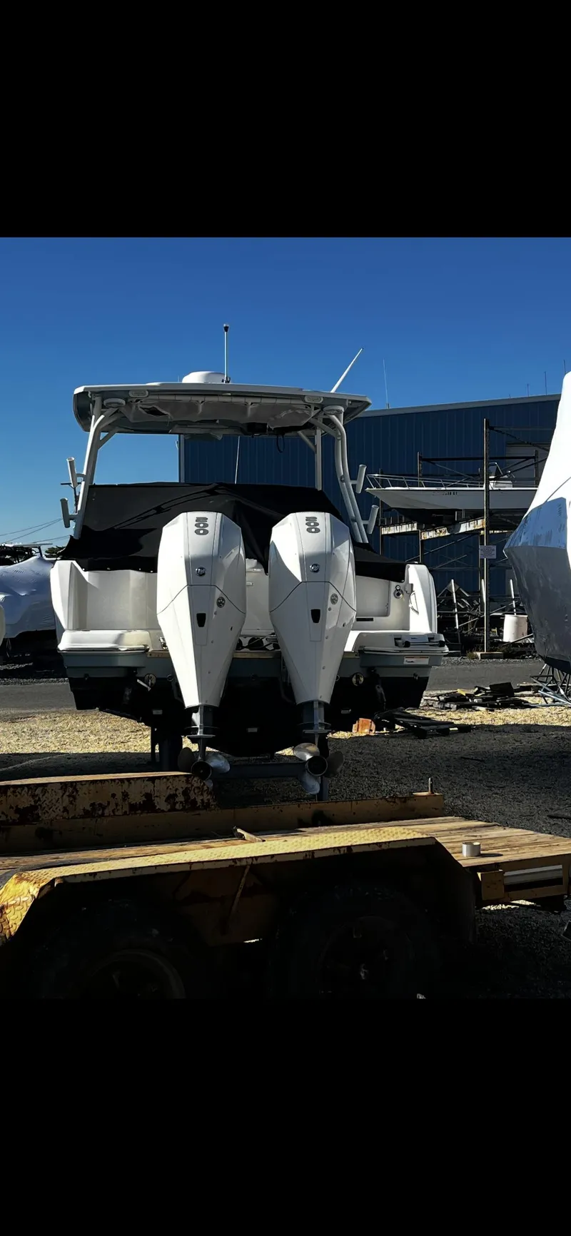 Slide: The Image of 2021 Sailfish 276 DC boat with dual outboard motors, docked outdoors. - 2