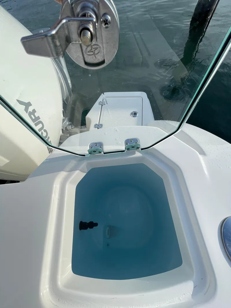Slide: The Image of 2021 Sailfish 276 DC boat with open livewell and glass cover, docked by the water. - 28