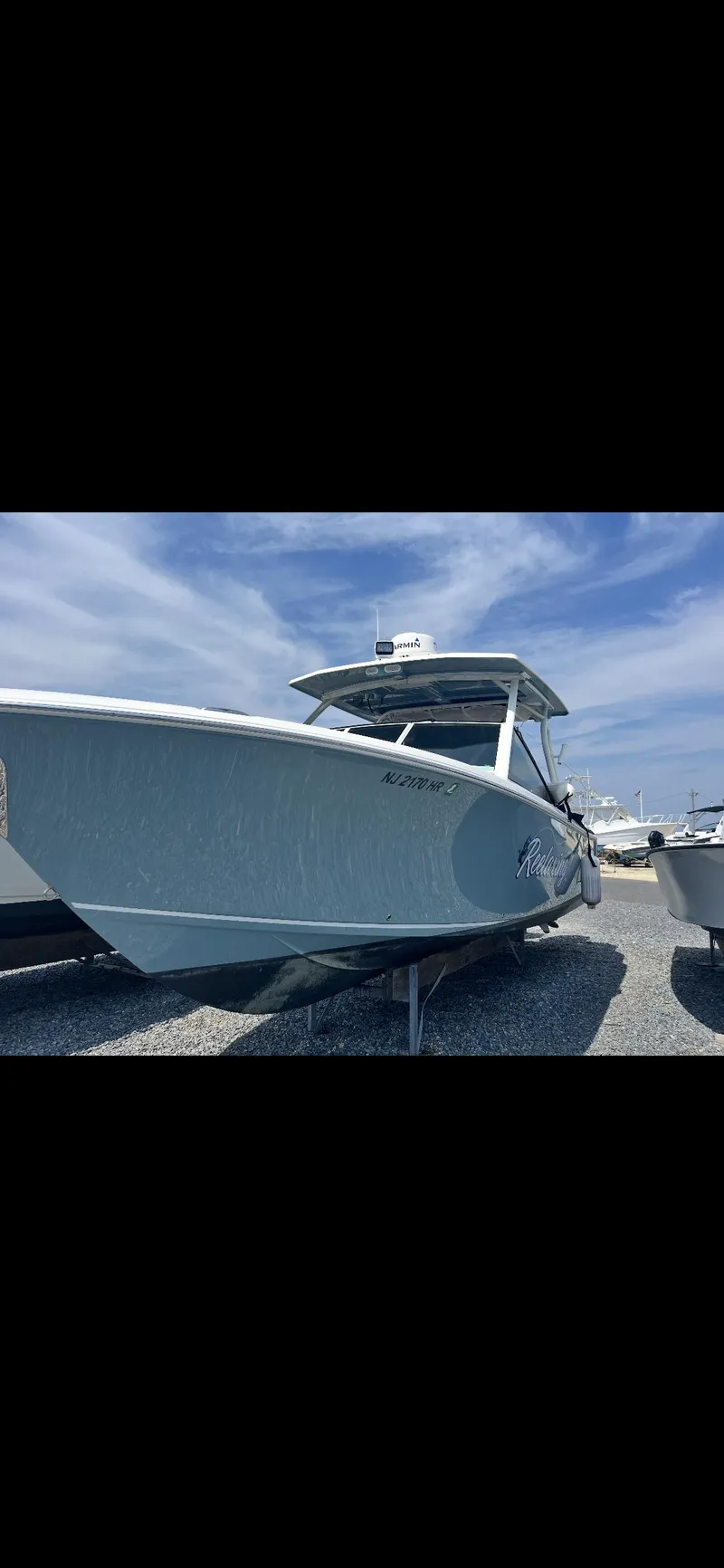 Slide: The Image of 2021 Sailfish 276 DC boat under clear blue sky on gravel lot. - 3