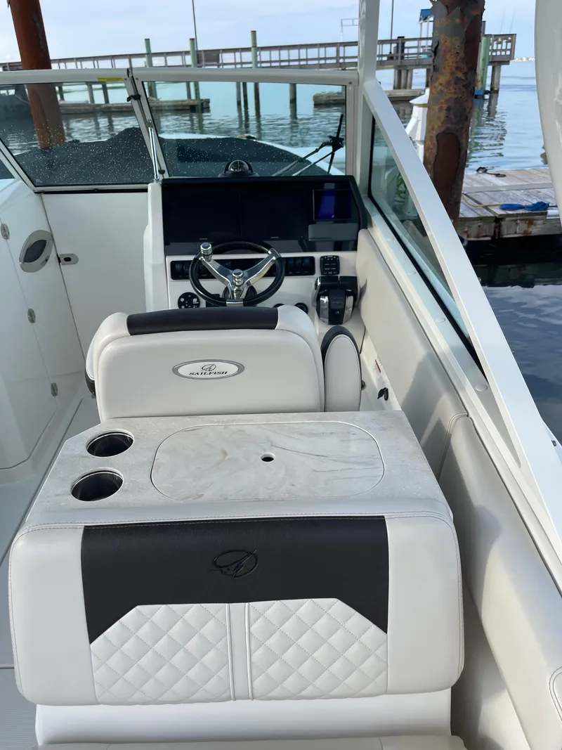 Slide: The Image of 2021 Sailfish 276 DC boat interior with steering wheel and seating near a dock. - 32
