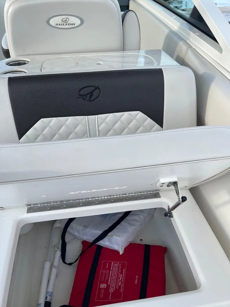 Slide: The Image of 2021 Sailfish 276 DC boat interior with storage compartment open, showcasing seating and safety equipment. - 33
