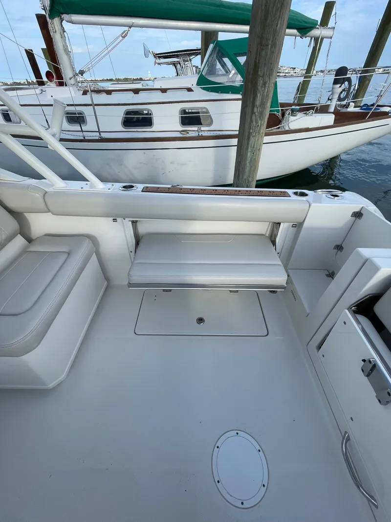 Slide: The Image of 2021 Sailfish 276 DC boat interior with seating, docked near another vessel. - 35