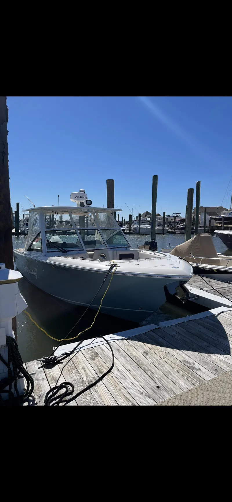 Slide: The Image of 2021 Sailfish 276 DC boat docked at a marina under clear blue skies. - 4