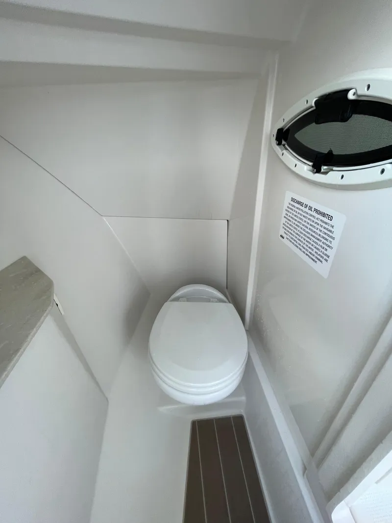 Slide: The Image of 2021 Sailfish 276 DC boat interior with compact marine toilet and porthole. - 44
