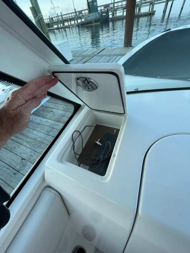 Slide: The Image of 2021 Sailfish 276 DC boat storage compartment with open hatch near dock. - 46