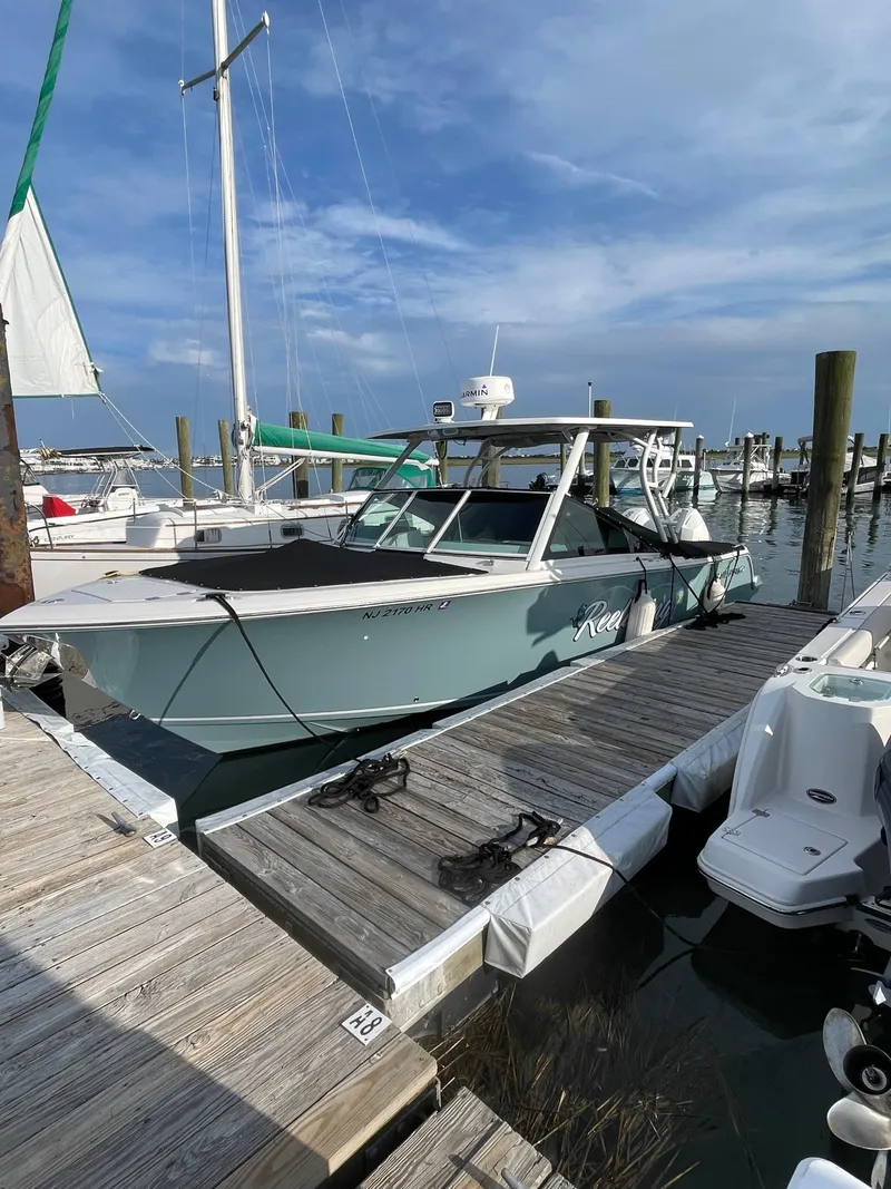 Slide: The Image of 2021 Sailfish 276 DC boat docked at a marina under a clear blue sky. - 7