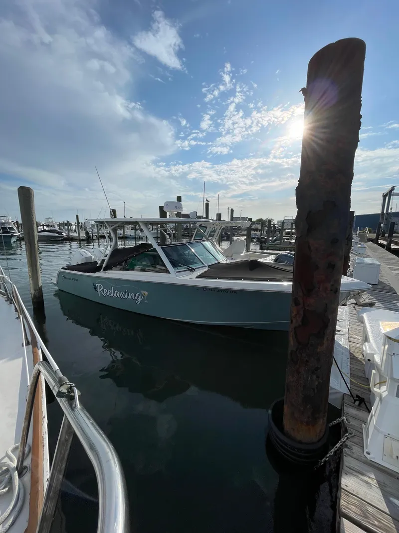 Slide: The Image of 2021 Sailfish 276 DC boat docked at marina under a partly cloudy sky. - 9