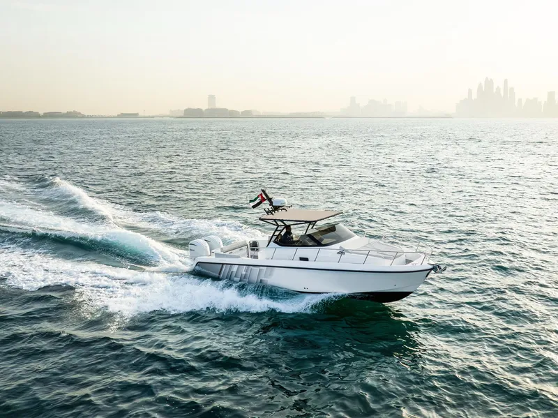 Slide: The Image of Oryx 32 FX 2025 boat cruising on open water with city skyline in background. - 11