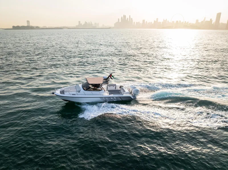 Slide: The Image of A 2025 Oryx 32 FX boat cruising on open water with a city skyline backdrop. - 12