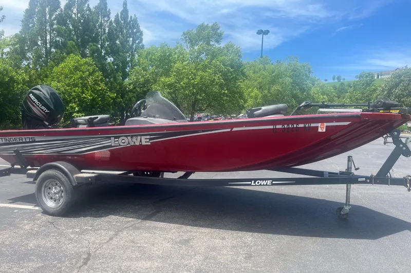 Slide: The Image of 2017 Lowe Stinger 175 boat on trailer, parked outdoors under clear sky. - 0