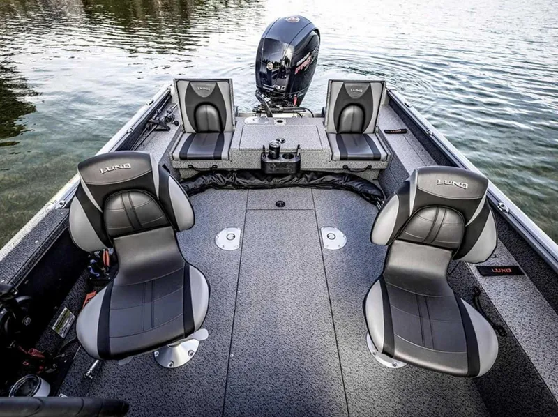 Slide: The Image of 2026 Lund 1875 Impact XS boat interior with four seats on a calm lake. - 16