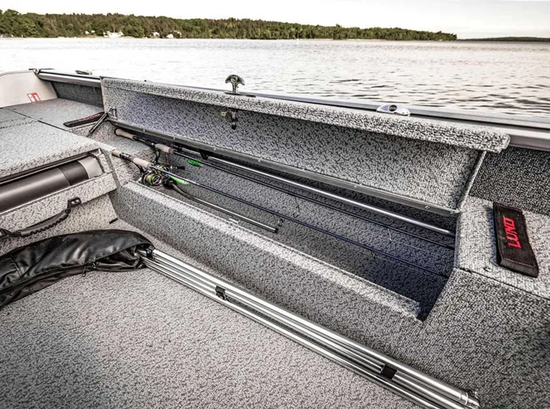 Slide: The Image of 2026 Lund 1875 Impact XS boat with open rod storage by a lake. - 17