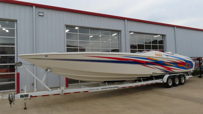 Slide: The Image of 2004 Cigarette 42 Tiger speedboat with vibrant graphics on a trailer, parked outside a garage. - 1