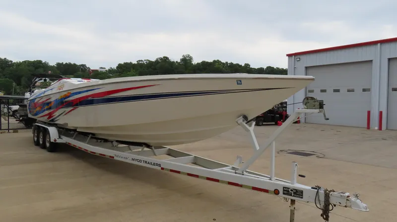 Slide: The Image of 2004 Cigarette 42 Tiger boat on trailer, parked outside a garage. - 2