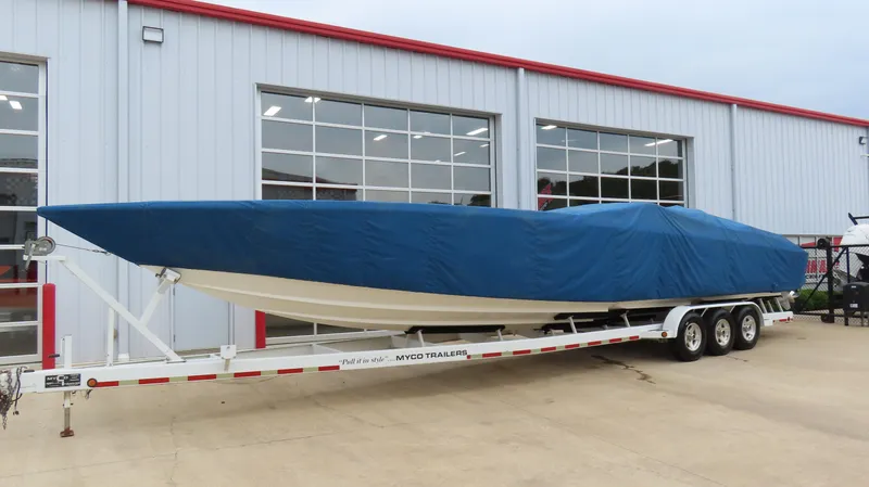 Slide: The Image of 2004 Cigarette 42 Tiger boat covered on trailer outside a garage. - 30