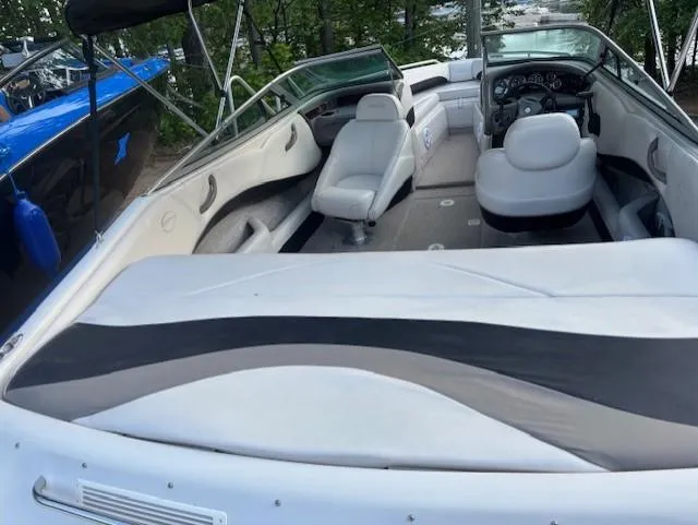 Slide: The Image of 1999 Crownline 202 boat interior with white seating and dashboard, parked outdoors. - 10