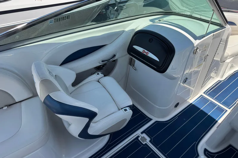 Slide: The Image of 2012 Chaparral 267 SSX boat interior with white and blue seating and sleek dashboard design. - 8