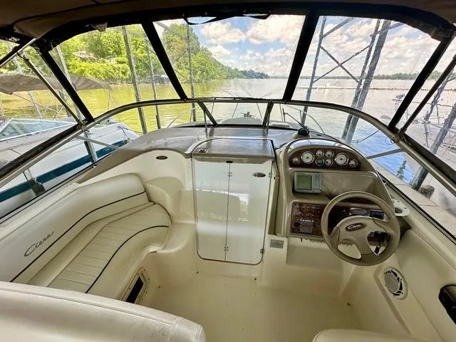 Slide: The Image of 2001 Bayliner 2855 Ciera boat interior with steering wheel and seating, docked by a scenic river. - 7