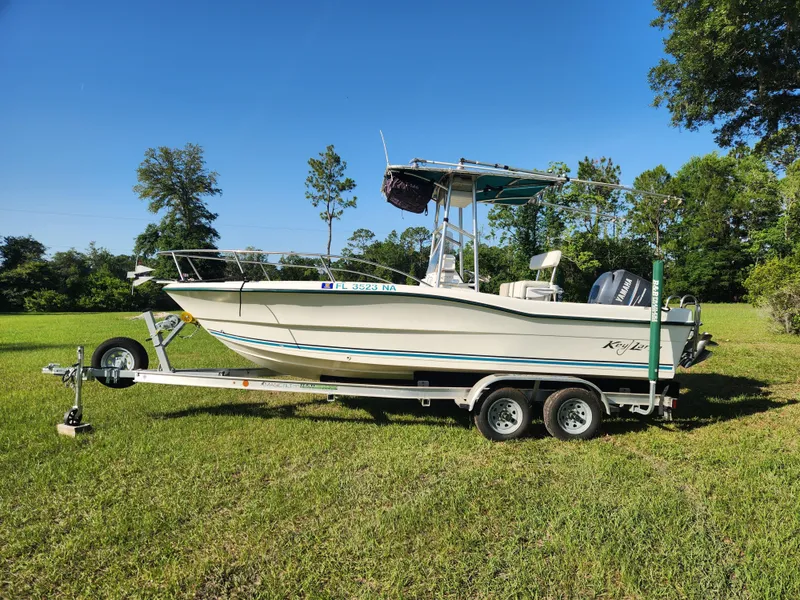The Image of 2005 Key Largo 210 CC boat on trailer, parked on grassy field. - 0