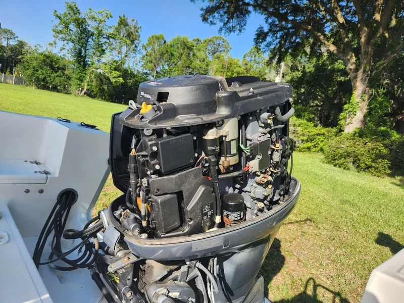 Slide: The Image of 2005 Key Largo 210 CC boat engine, open cover, in a grassy outdoor setting. - 18