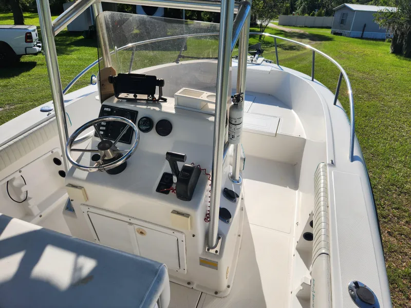 Slide: The Image of 2005 Key Largo 210 CC boat interior with steering console and seating, parked on grass. - 23
