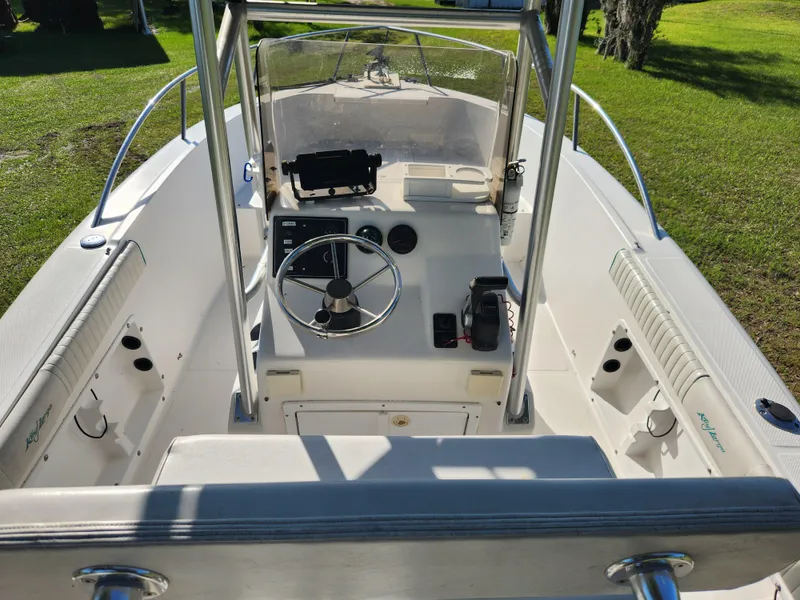 Slide: The Image of 2005 Key Largo 210 CC boat interior with steering wheel and console, parked on grass. - 25