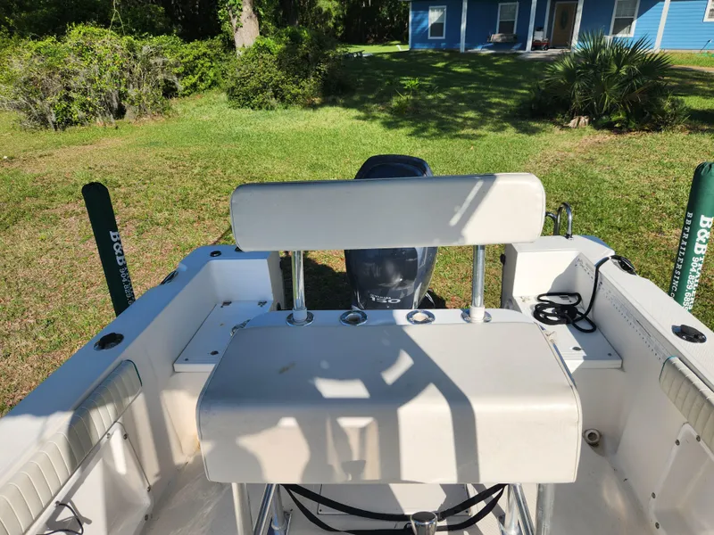 Slide: The Image of 2005 Key Largo 210 CC boat interior with seating and motor, set in a grassy yard. - 30