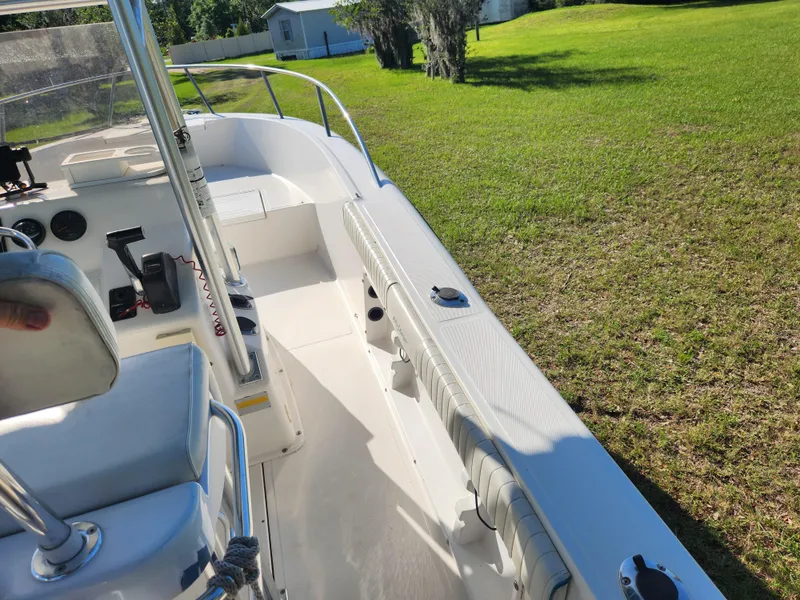 Slide: The Image of 2005 Key Largo 210 CC boat interior with seating and controls, parked on grassy area. - 32