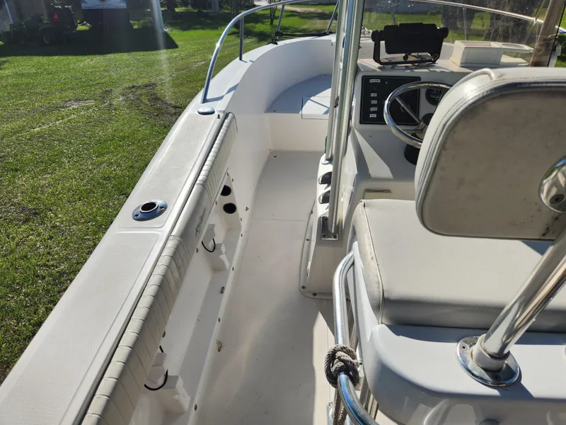 Slide: The Image of 2005 Key Largo 210 CC boat interior with steering wheel and seating, on grassy background. - 34