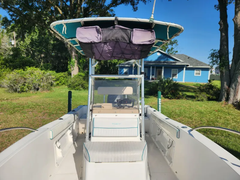 Slide: The Image of 2005 Key Largo 210 CC boat with canopy, parked on grass near a blue house. - 36