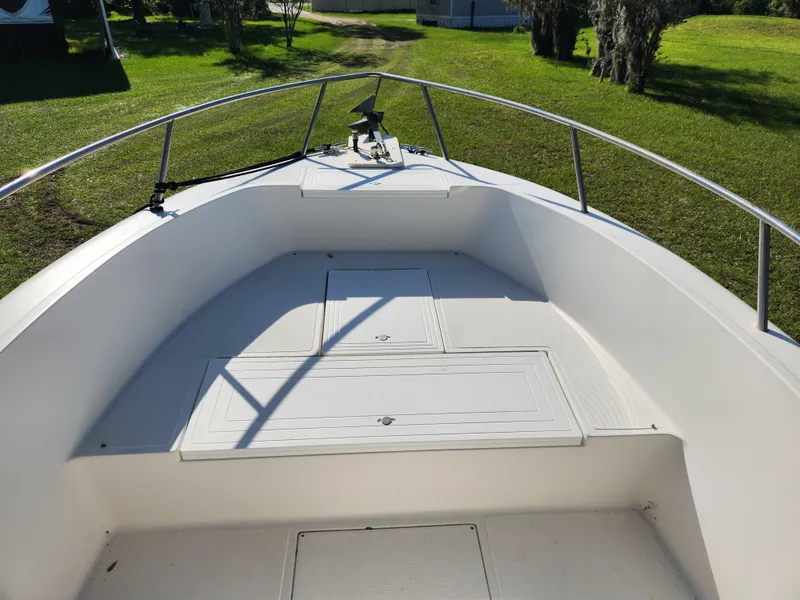 Slide: The Image of 2005 Key Largo 210 CC boat deck with storage compartments, surrounded by green grass. - 37