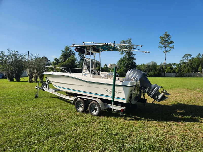 Slide: The Image of 2005 Key Largo 210 CC boat on trailer in grassy field under clear blue sky. - 4