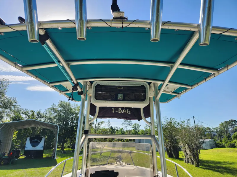 Slide: The Image of 2005 Key Largo 210 CC boat with blue canopy and rod holders, parked outdoors. - 41
