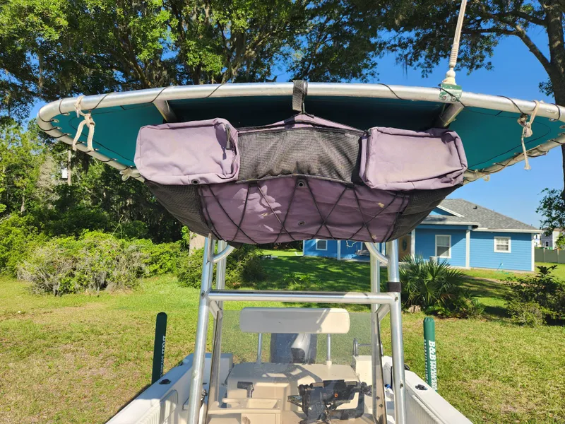 Slide: The Image of Key Largo 210 CC boat, 2005 model, with storage bags under a canopy, parked on grass. - 42