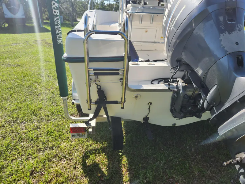 Slide: The Image of 2005 Key Largo 210 CC boat rear view with ladder and outboard motor on grass. - 7