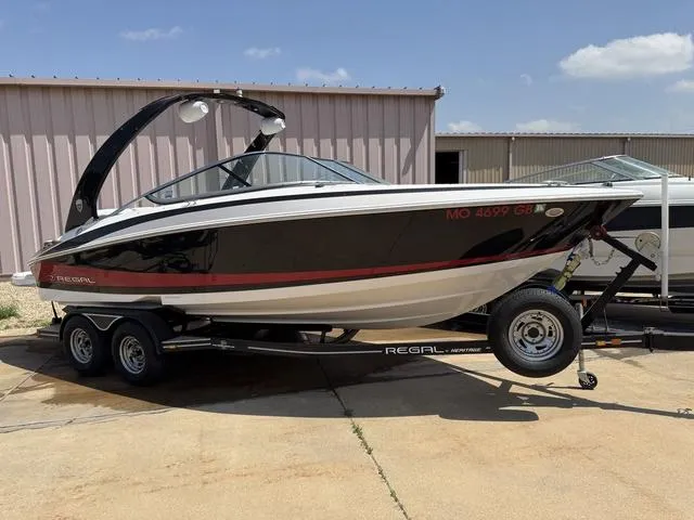 Slide: The Image of 2014 Regal 2300 boat on trailer, black and white design, parked outdoors. - 1