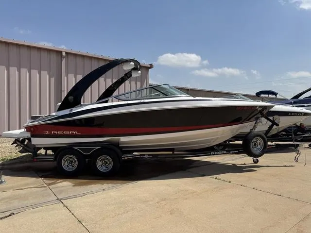 Slide: The Image of 2014 Regal 2300 boat on trailer, parked outdoors under clear sky. - 2