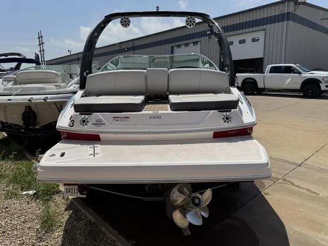 Slide: The Image of 2014 Regal 2300 boat with dual propellers, parked outdoors near a warehouse. - 3