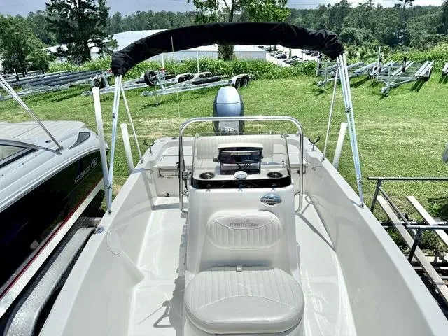 Slide: The Image of 2012 NAUTIC STAR 1810 CC boat with console and seating, parked on grass. - 8