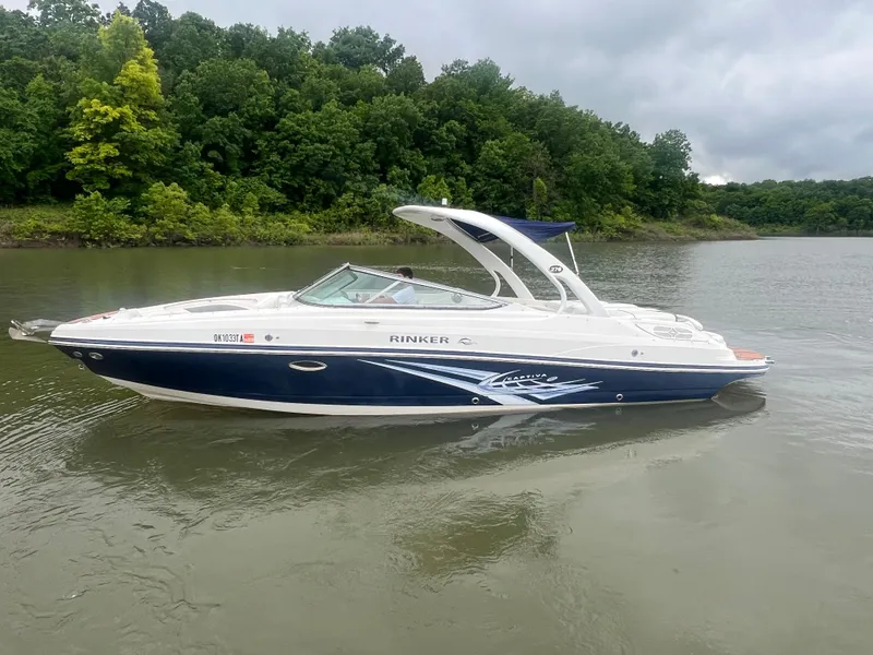 Slide: The Image of 2011 Rinker 276 Captiva Bowrider on a calm lake with lush green shoreline. - 0