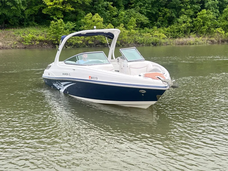 Slide: The Image of 2011 Rinker 276 Captiva Bowrider on a calm lake with lush green shoreline. - 1