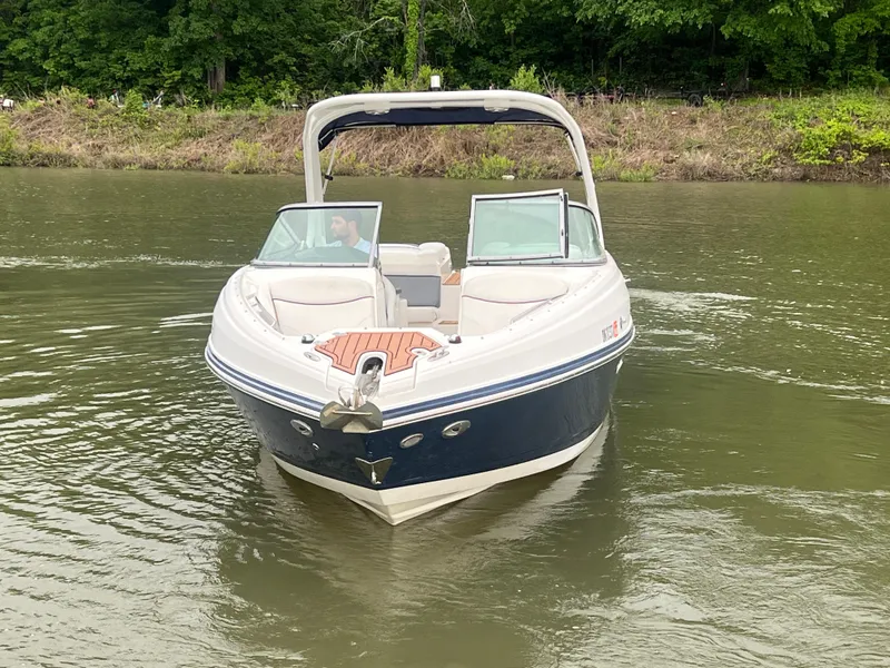 Slide: The Image of 2011 Rinker 276 Captiva Bowrider on a calm river, surrounded by lush greenery. - 11