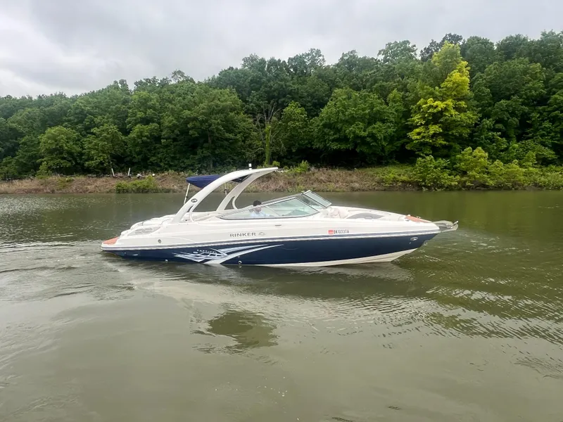 Slide: The Image of 2011 Rinker 276 Captiva Bowrider cruising on a calm lake with lush green trees. - 13