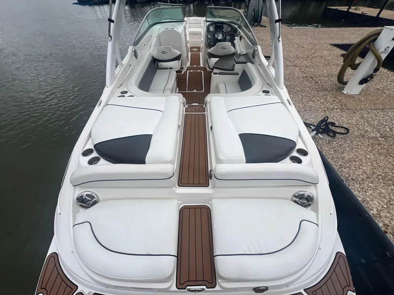 Slide: The Image of 2011 Rinker 276 Captiva Bowrider with white seating and wood accents docked by the water. - 16