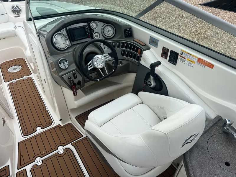 Slide: The Image of 2011 Rinker 276 Captiva Bowrider cockpit with steering wheel, gauges, and white captain's chair. - 22